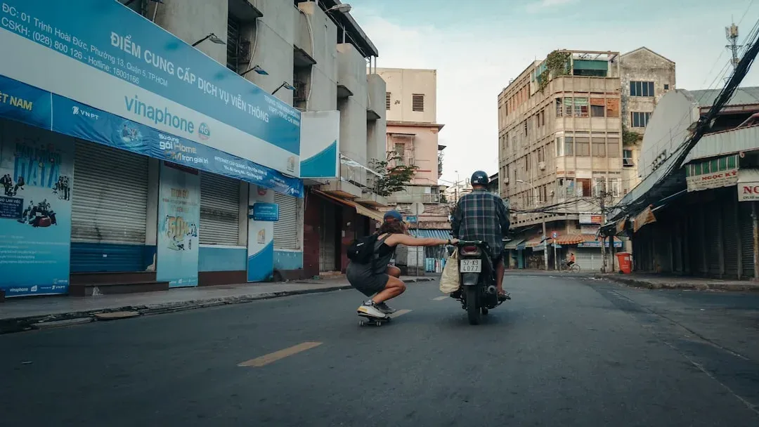 A scooter parked on a road with a bustling cityscape in the background